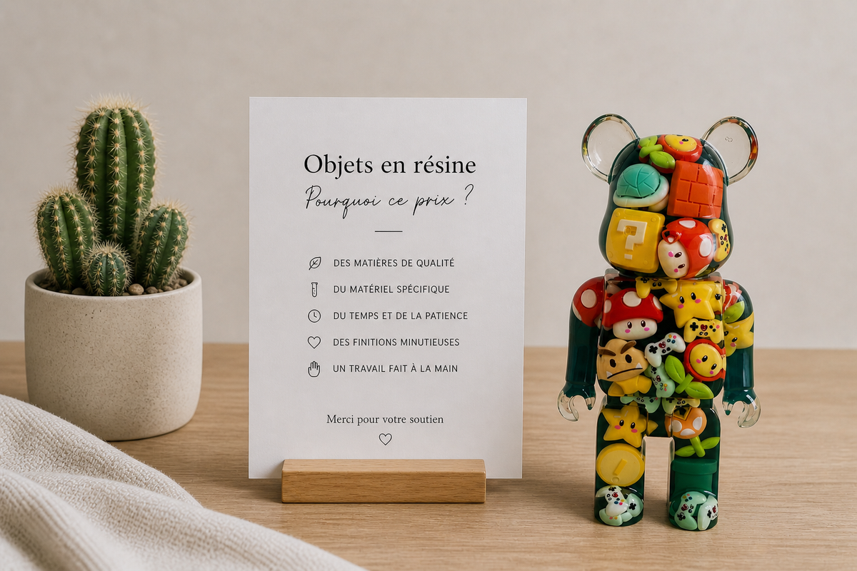 Objet décoratif en résine époxy fait main avec figurine ours transparente remplie d’inclusions colorées, posé sur une table avec un cactus et une affiche explicative sur le fait main