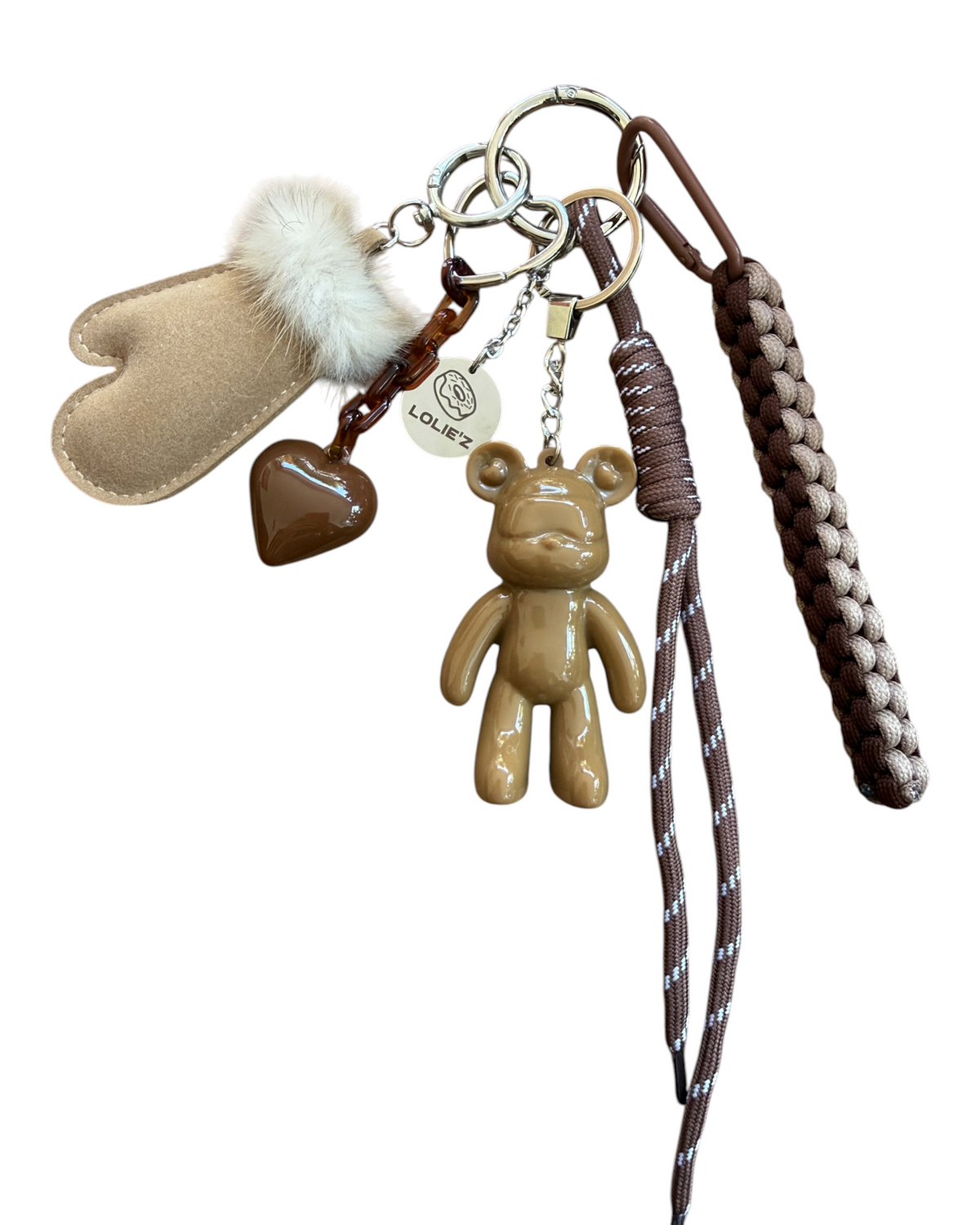 Grigri Urban Ted Miss Caramel accroché à un sac à main taupe dans une ambiance hivernale, avec ours caramel brillant, cœur chocolat et moufle beige.