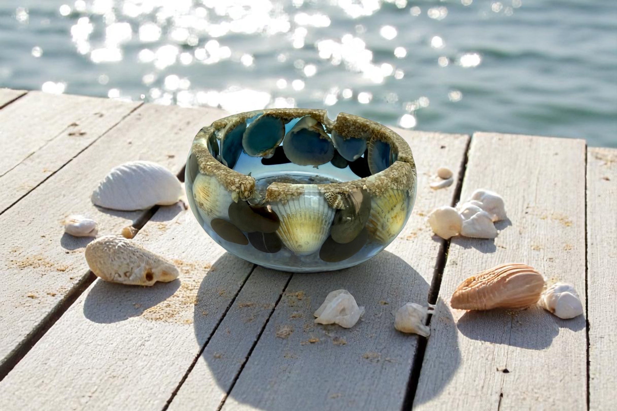 Collection de cendriers en résine époxy faits main, grands formats ronds et petits carrés sur le thème de la mer, décorés de sable, galets et coquillages.