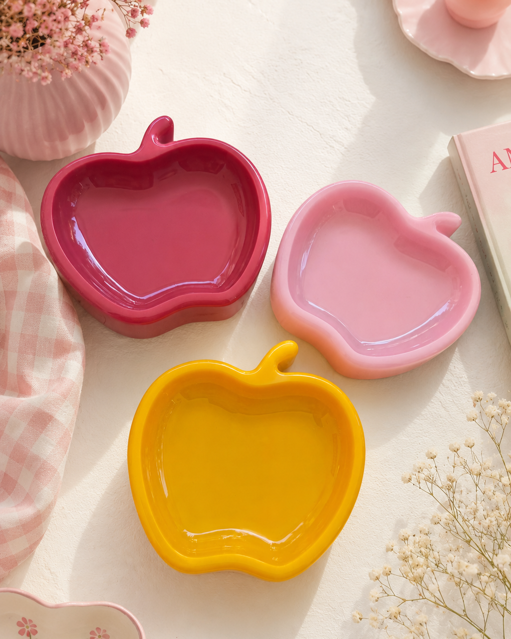 Trois vide-poches en forme de pomme en résine époxy colorée, présentés dans une décoration douce et lumineuse aux accents pastel.