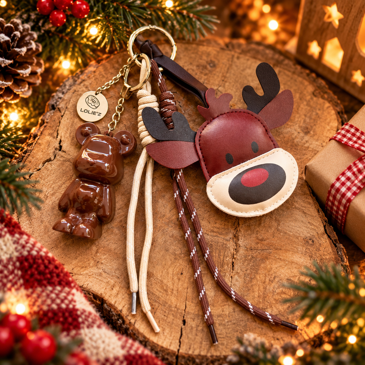 Grigri de sac de Noël Lolie’z composé d’un ours en résine chocolat, d’un renne bordeaux et de cordons décoratifs, présenté sur un support en bois dans une ambiance festive et chaleureuse.