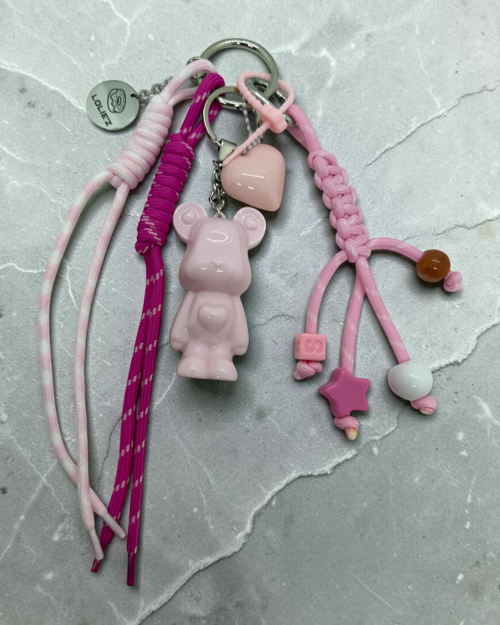 Grigri Marley Marshmallow rose avec ourson en résine époxy, cordons rose et fuchsia, cœur et perles colorées.