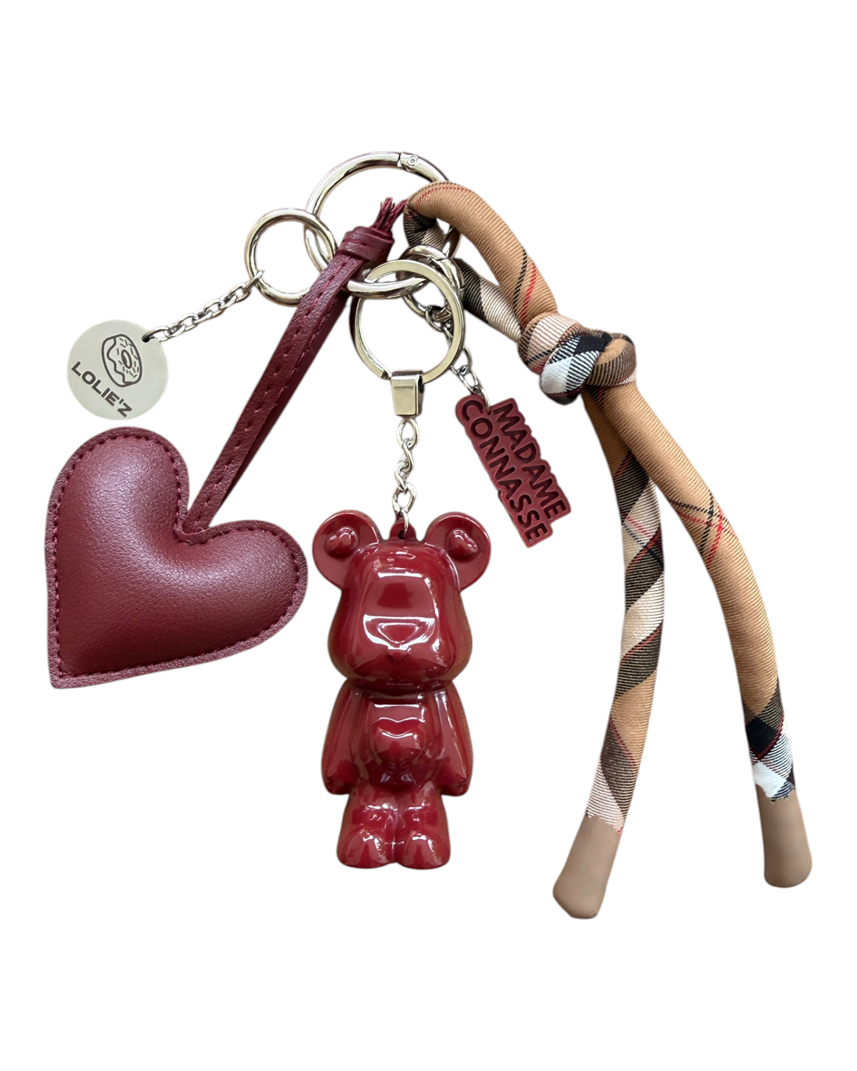 Marley Onirique, grigri de sac artisanal Lolie’z composé d’un ourson bordeaux en résine, d’un cœur, d’un foulard à carreaux et d’une médaille Lolie’z gravée.