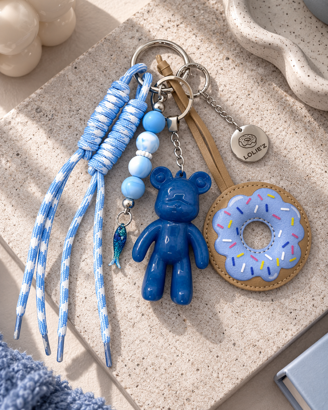 Grigri de sac Lolie’z bleu avec Teddy’z en résine époxy, donut, cordons bleu et blanc, perles et breloque poisson, assemblé à la main en France.