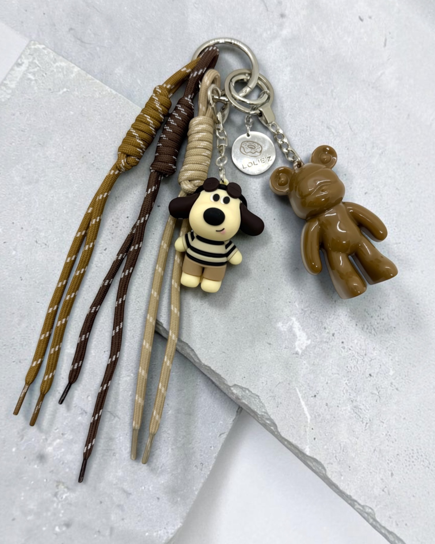 Grigri de sac Lolie’z aux tons camel, marron et beige avec Teddy’z en résine époxy, breloque chien et cordons assortis, assemblé à la main en France.