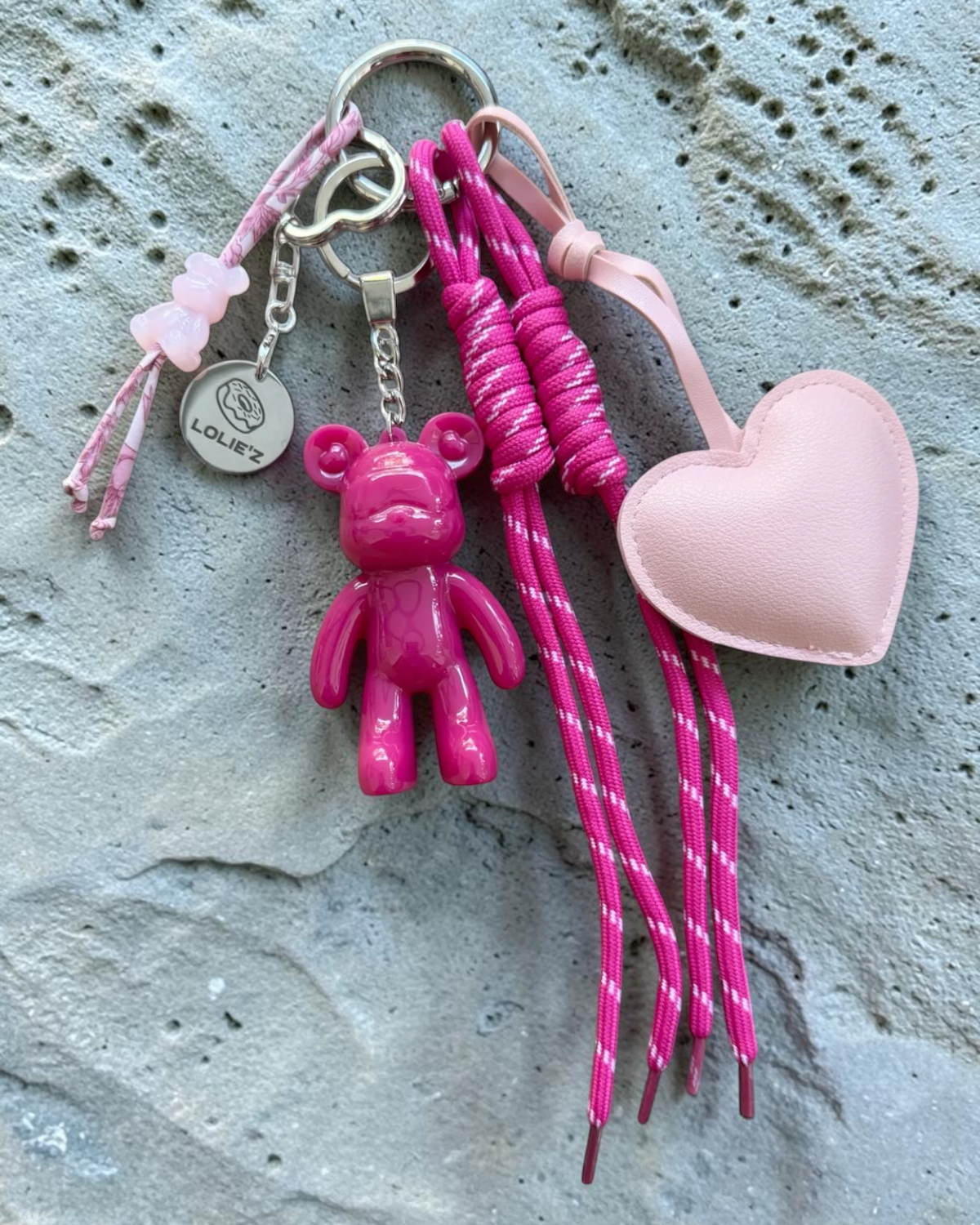 Grigri de sac Lolie’z rose fuchsia avec Teddy’z en résine époxy, cœur rose poudré, cordons fuchsia et petite breloque ours, assemblé à la main en France.