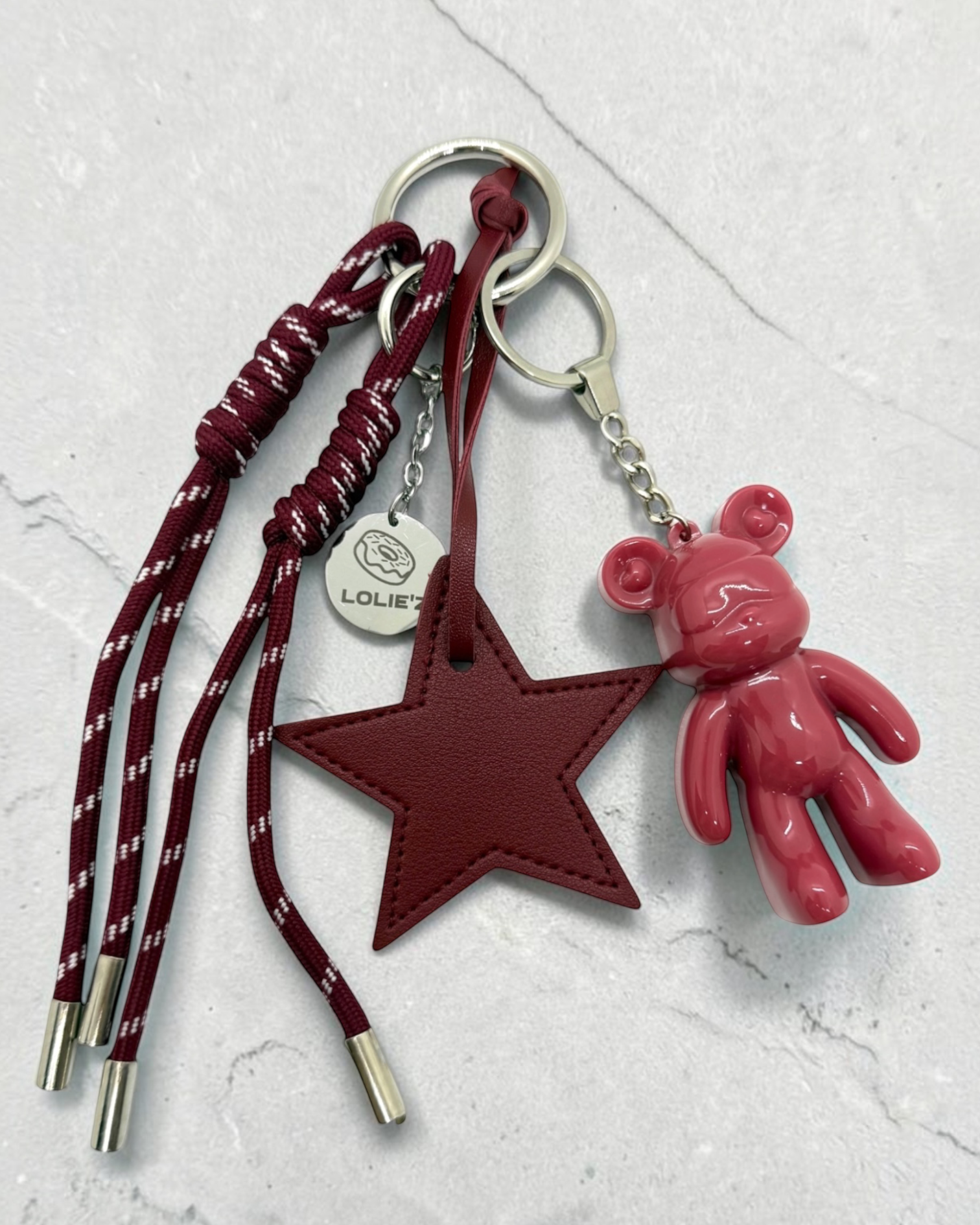 Grigri de sac Lolie’z avec Teddy’z rose en résine époxy, grande étoile bordeaux, cordons assortis et médaille gravée, assemblé à la main en France.
