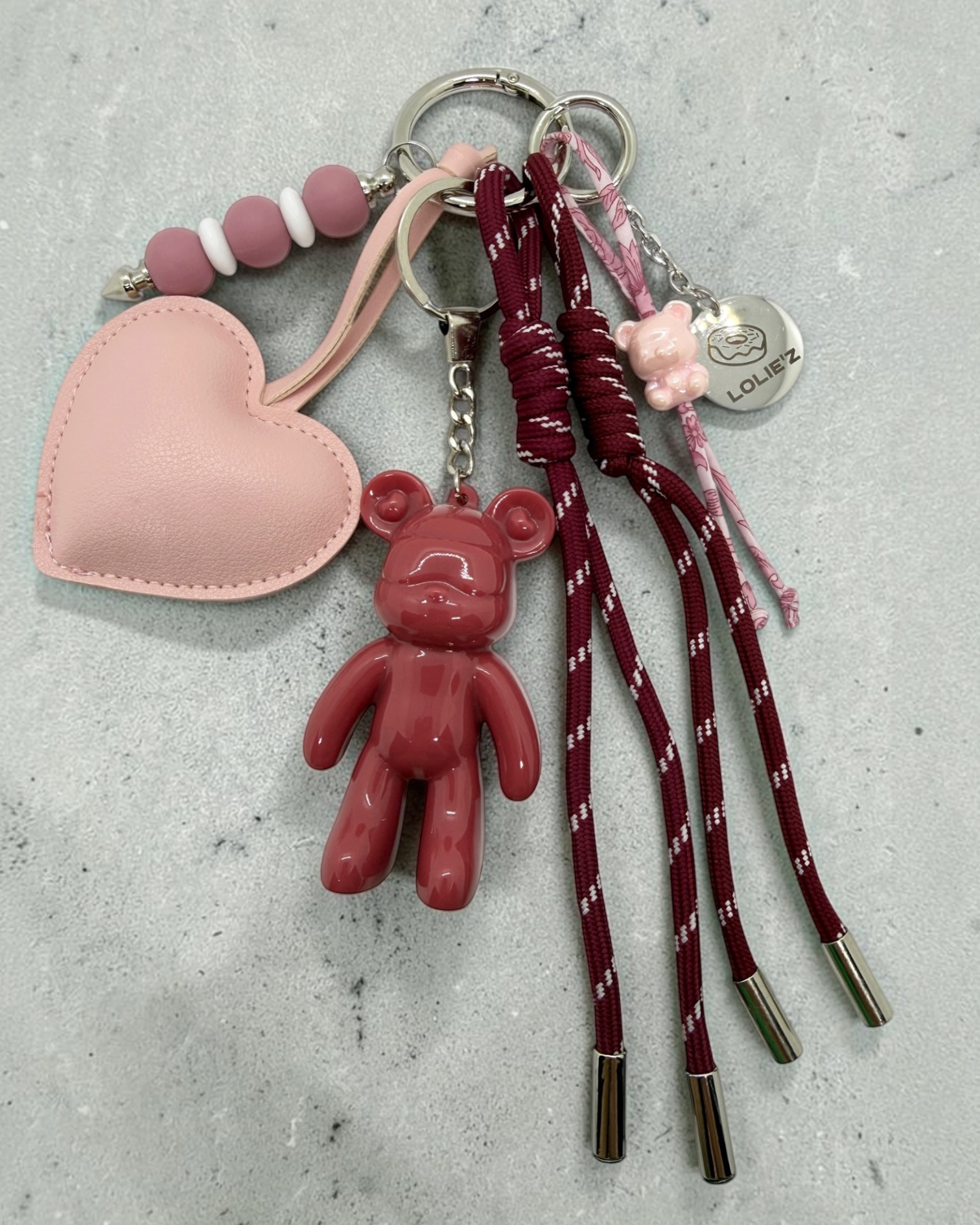 Grigri de sac Lolie’z rose avec Teddy’z en résine époxy, grand cœur rose, cordons bordeaux, perles et petite breloque ours, assemblé à la main en France.