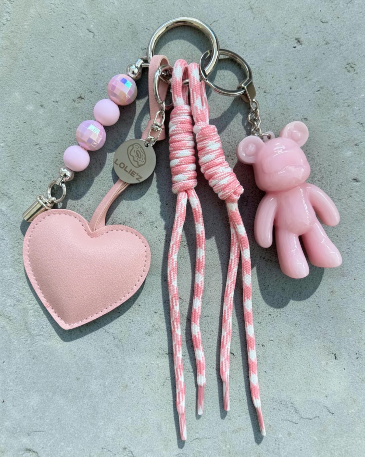 Grigri de sac Lolie’z rose avec Teddy’z en résine époxy, grand cœur rose, perles et cordons rose et blanc, création assemblée à la main en France.