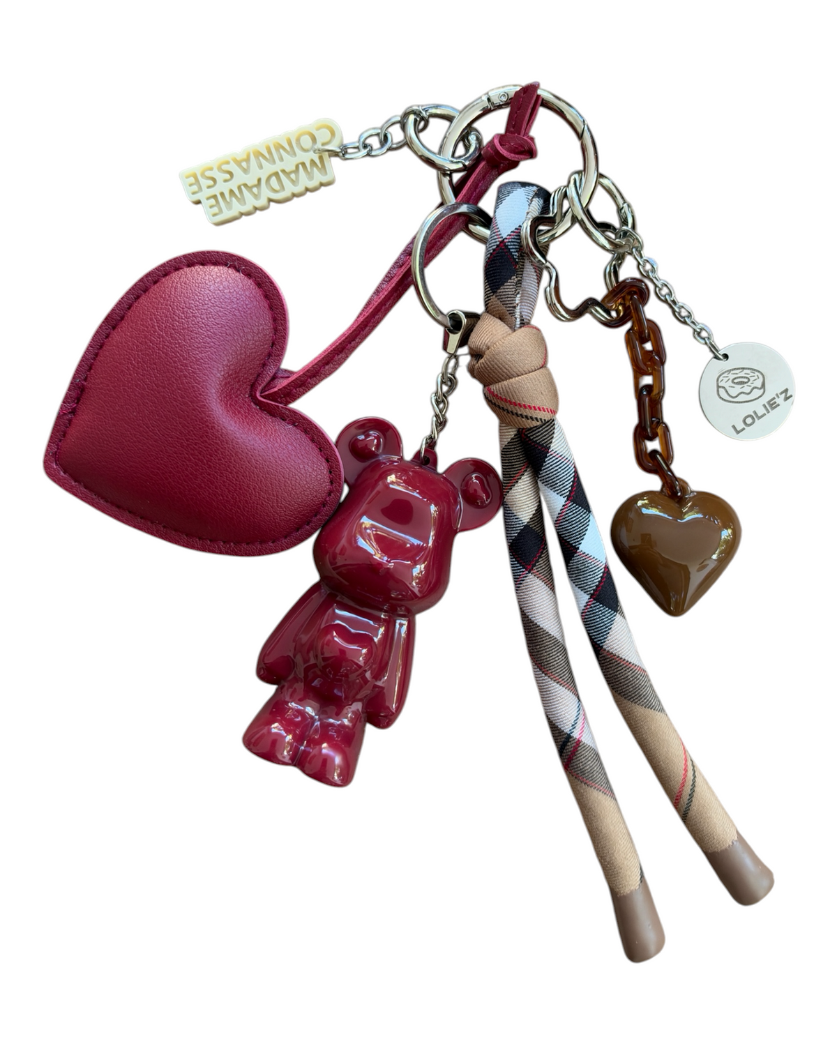 Pépitas, grigri Marley bordeaux fait main avec cœur bordeaux, ruban tartan et breloques, présenté sur fond blanc.