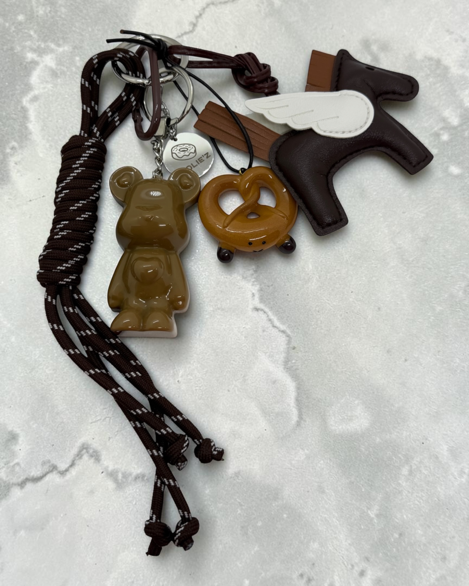 Marley Wild Ride, grigri de sac caramel en résine époxy avec cheval ailé, cordons bruns et médaille Lolie’z gravée.