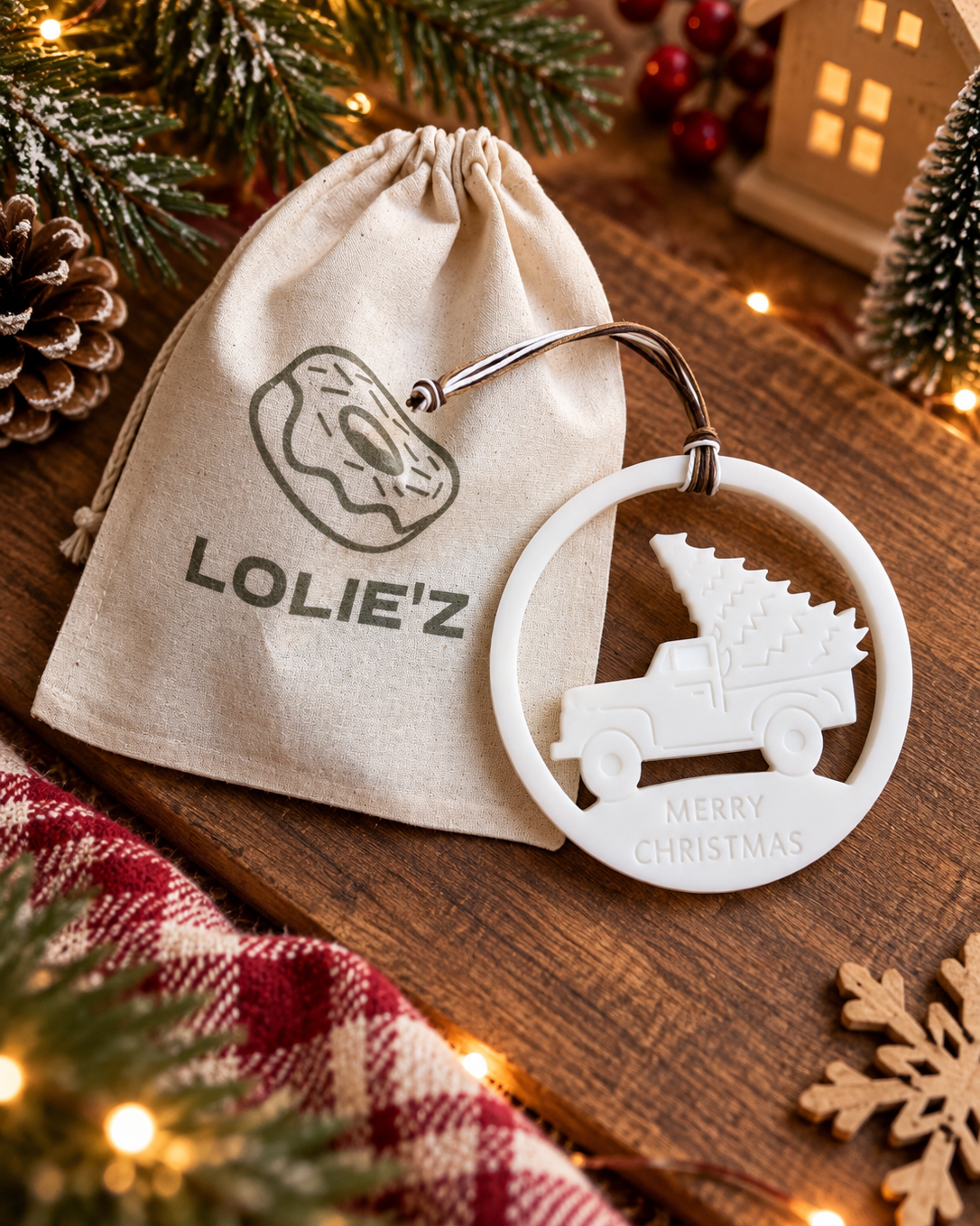 Suspension Santa’s Pickup en résine époxy avec voiture transportant un sapin, présentée dans une ambiance de Noël Lolie’z.