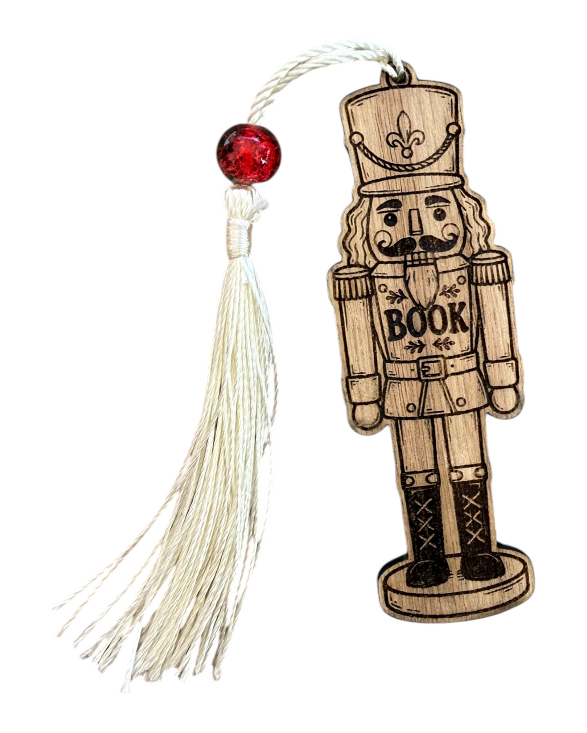 Marque-page NUTCRACKER Lolie’z en bois découpé et gravé en forme de casse-noisette avec inscription BOOK, pompon écru et perle rouge.