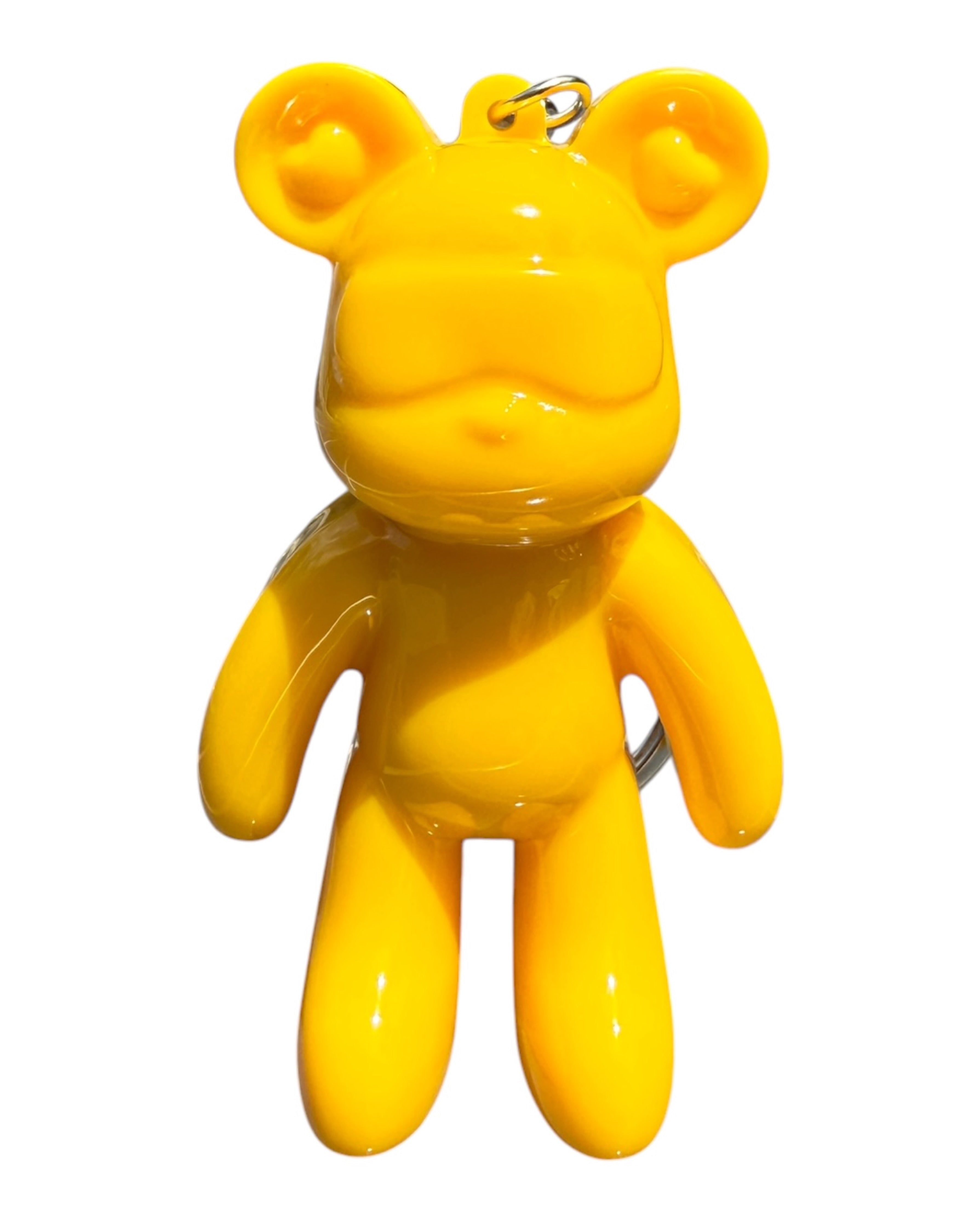 Petit ours jaune en résine époxy brillante accroché comme accessoire tendance sur fond moderne et lumineux.