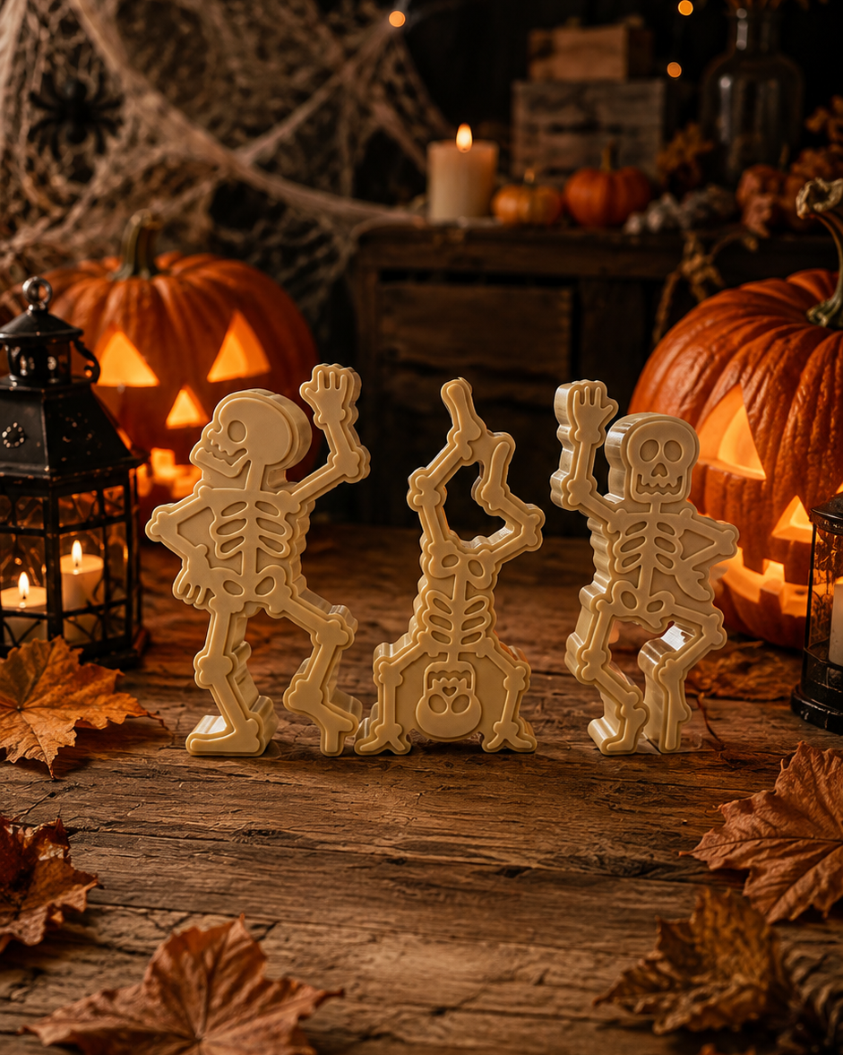 Trio de squelettes décoratifs Lolie’z en résine époxy, mis en scène dans un décor d’Halloween avec citrouilles, lanternes et feuilles d’automne.