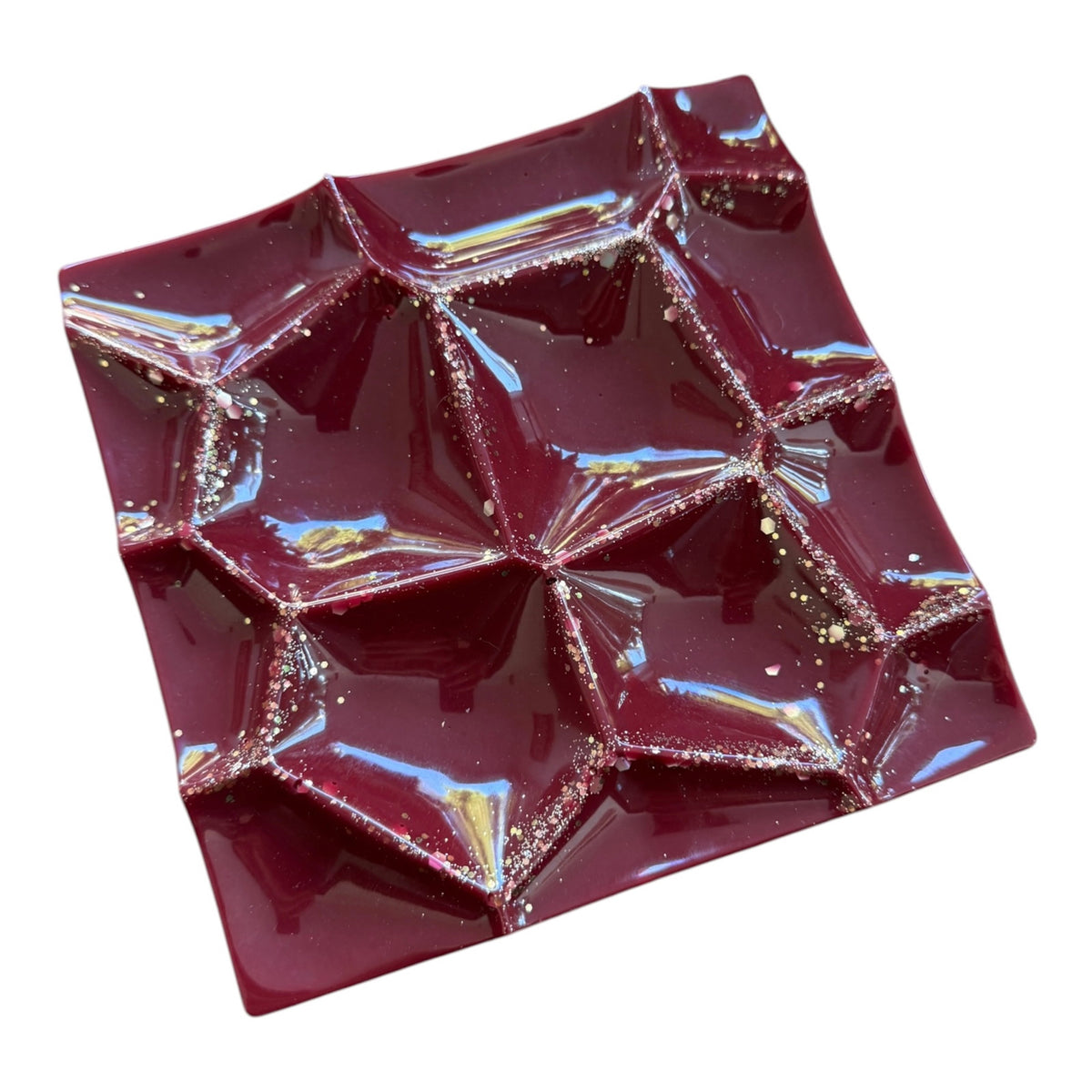 Vide-poche artisanal en résine époxy bordeaux profond, à la finition ultra brillante, avec des reliefs géométriques en facettes et de délicats éclats dorés. Une pièce décorative pour ranger bijoux et petits accessoires.