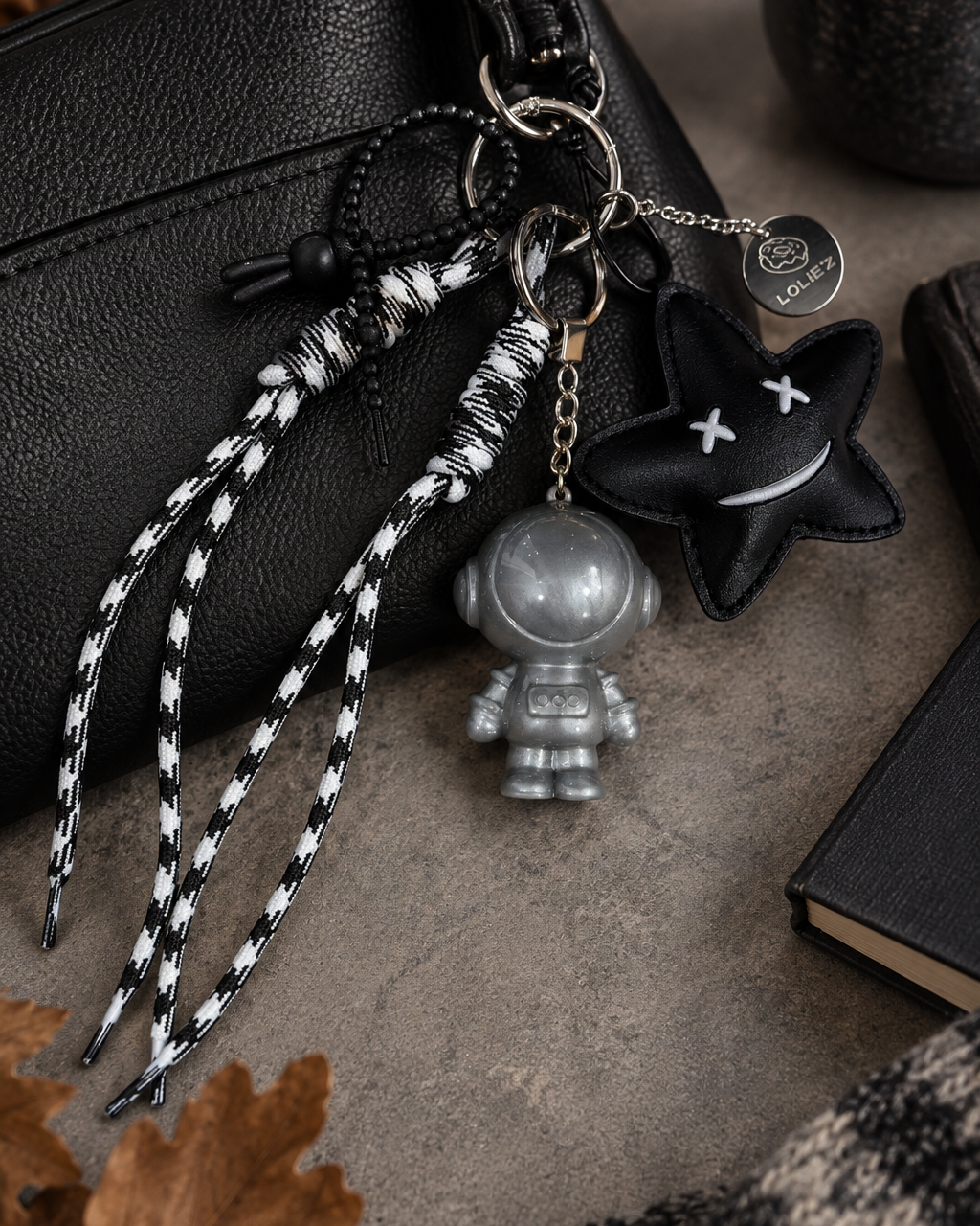 Grigri de sac Andy Astro Star avec astronaute argenté, étoile noire et longs cordons noir et blanc, création artisanale Lolie’z.