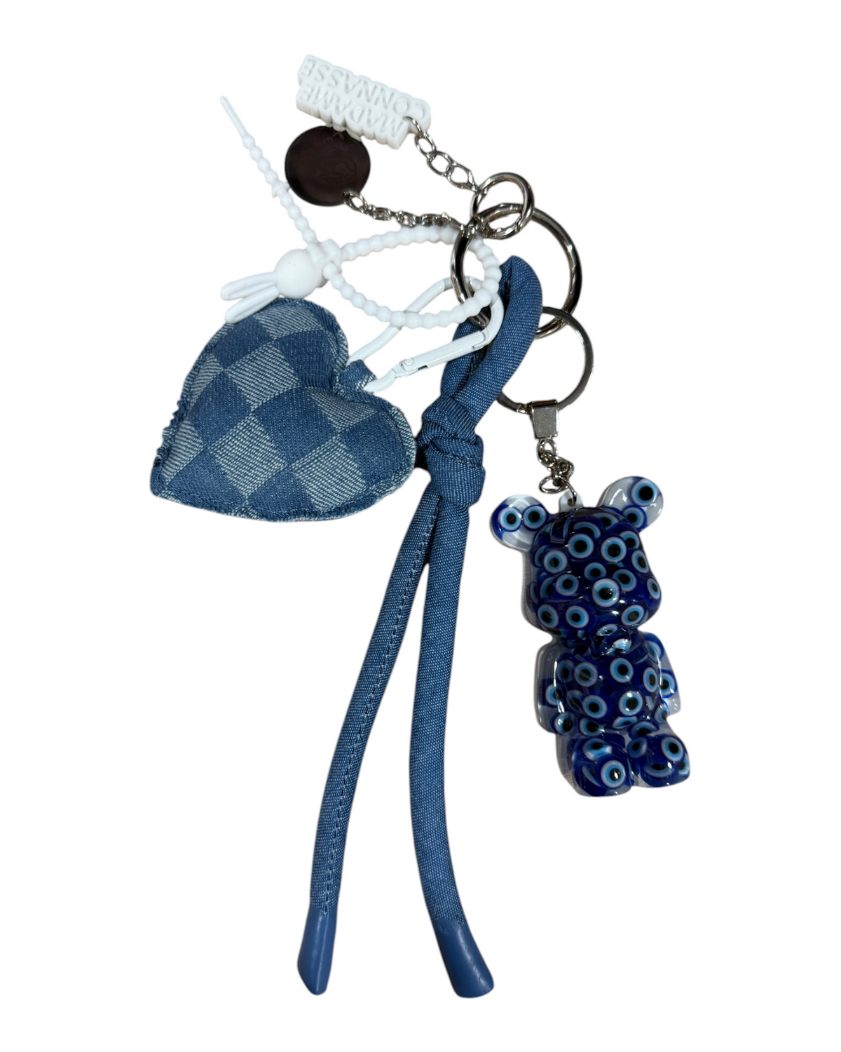 Détails du grigri Denim Voodoo avec Teddy en résine, cœur textile en denim, perles, liens noués et breloques métalliques