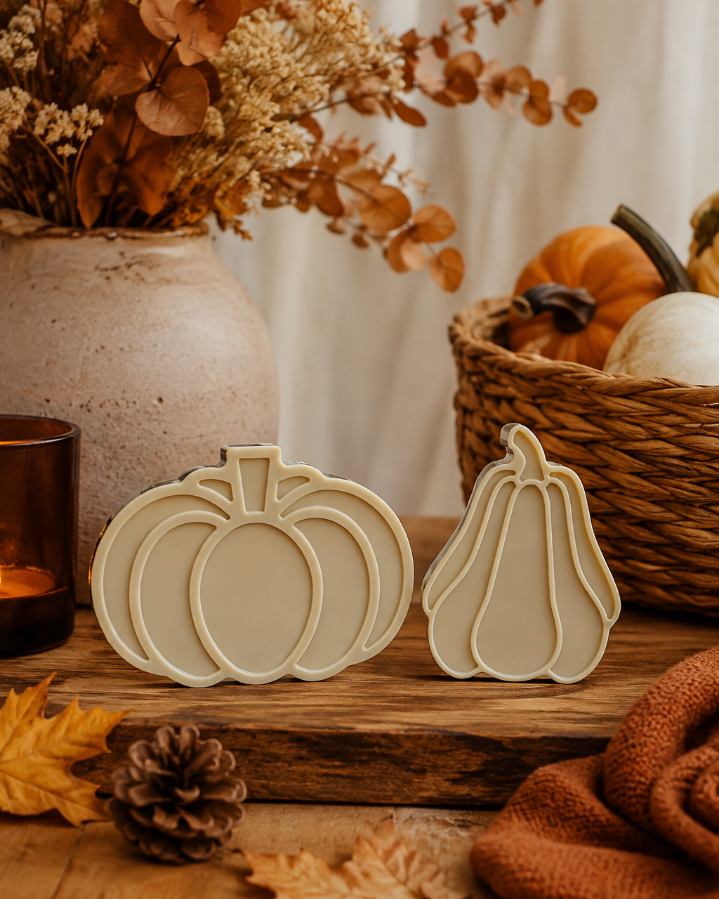 Duo de courges décoratives beige en résine époxy fait main, présenté dans une décoration automnale avec citrouilles, feuilles et matières naturelles.