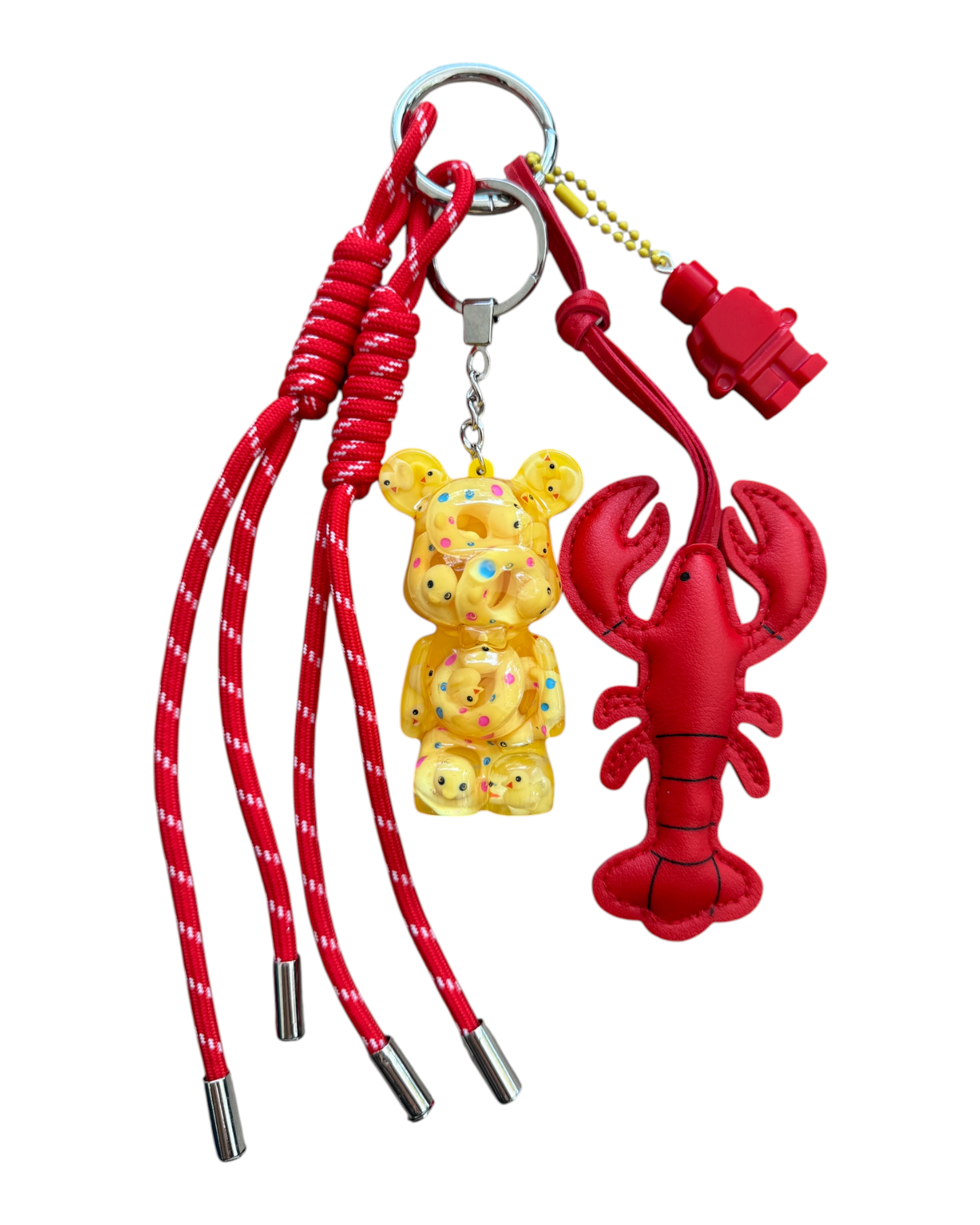 Grigri Lobster Yellow avec Teddy'z jaune en résine rempli de mini canetons, cordon rouge et homard décoratif rouge.
