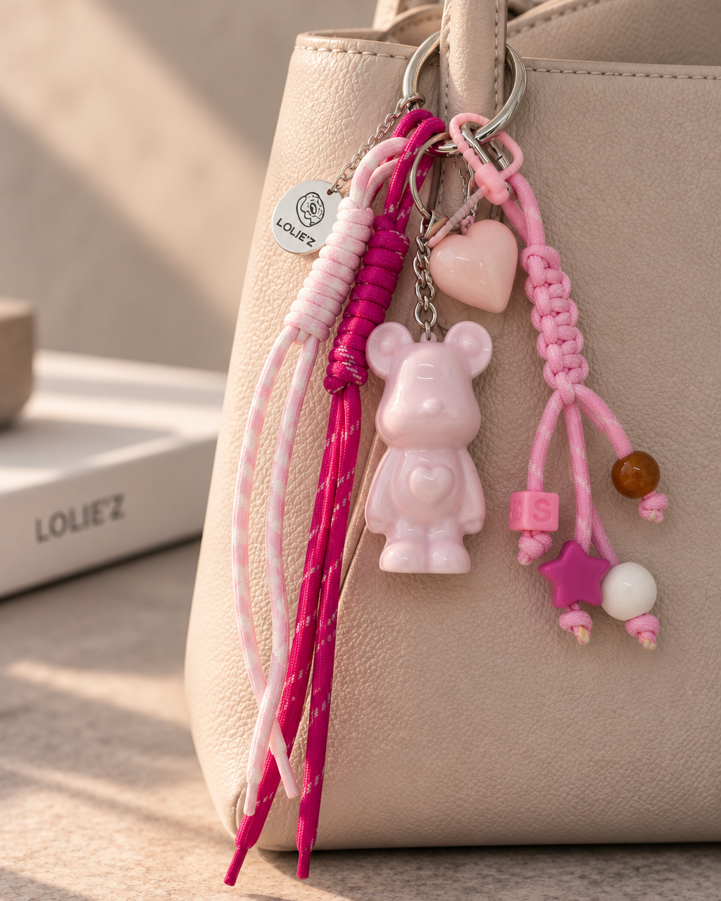 Grigri Marley Marshmallow rose avec ourson en résine époxy, cordons rose et fuchsia, cœur et perles colorées.