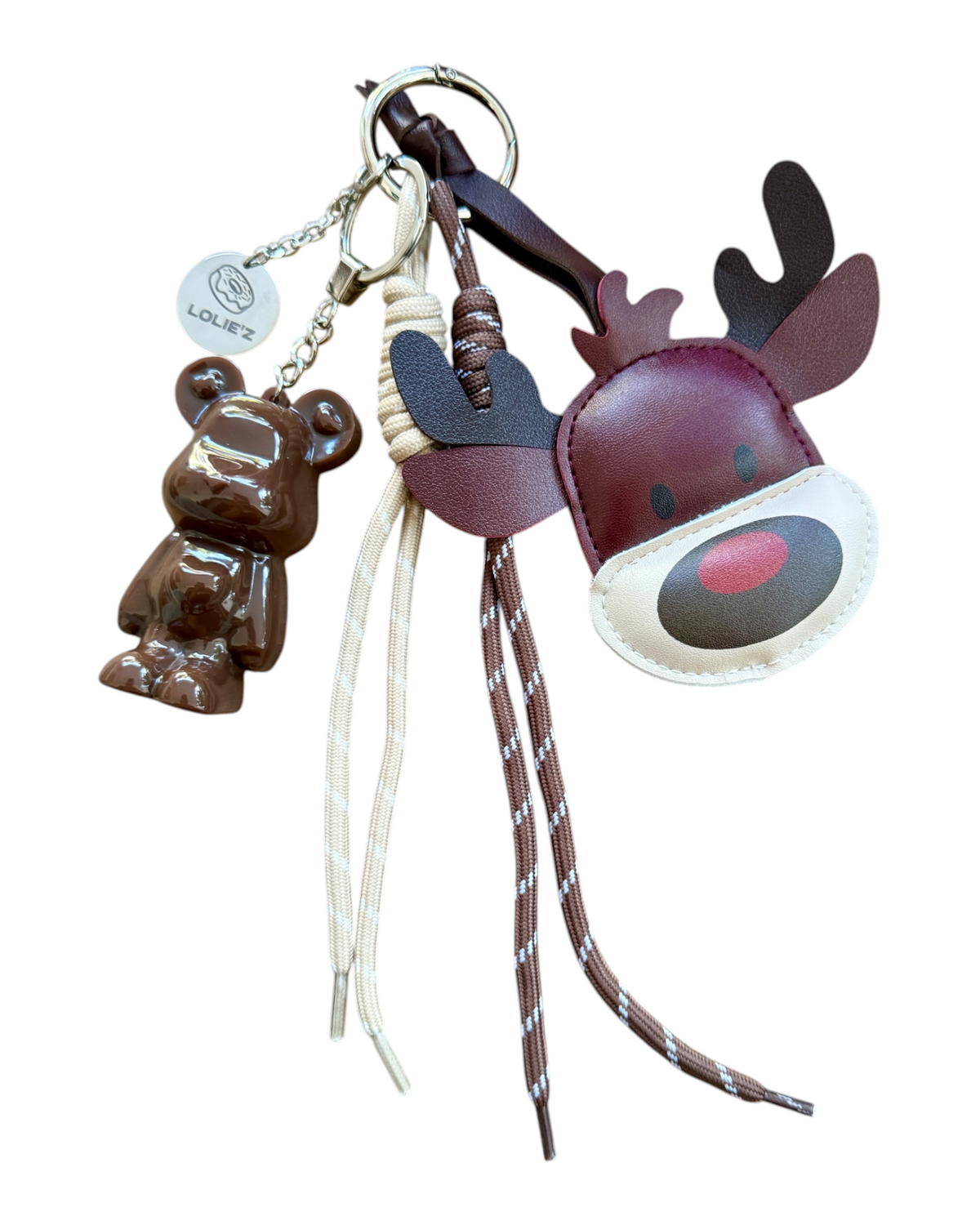 Grigri Marley Dear Rudolph présenté sur fond blanc, avec un ours chocolat brillant en résine époxy, une tête de renne bordeaux, des cordons crème et marron et des attaches métalliques.