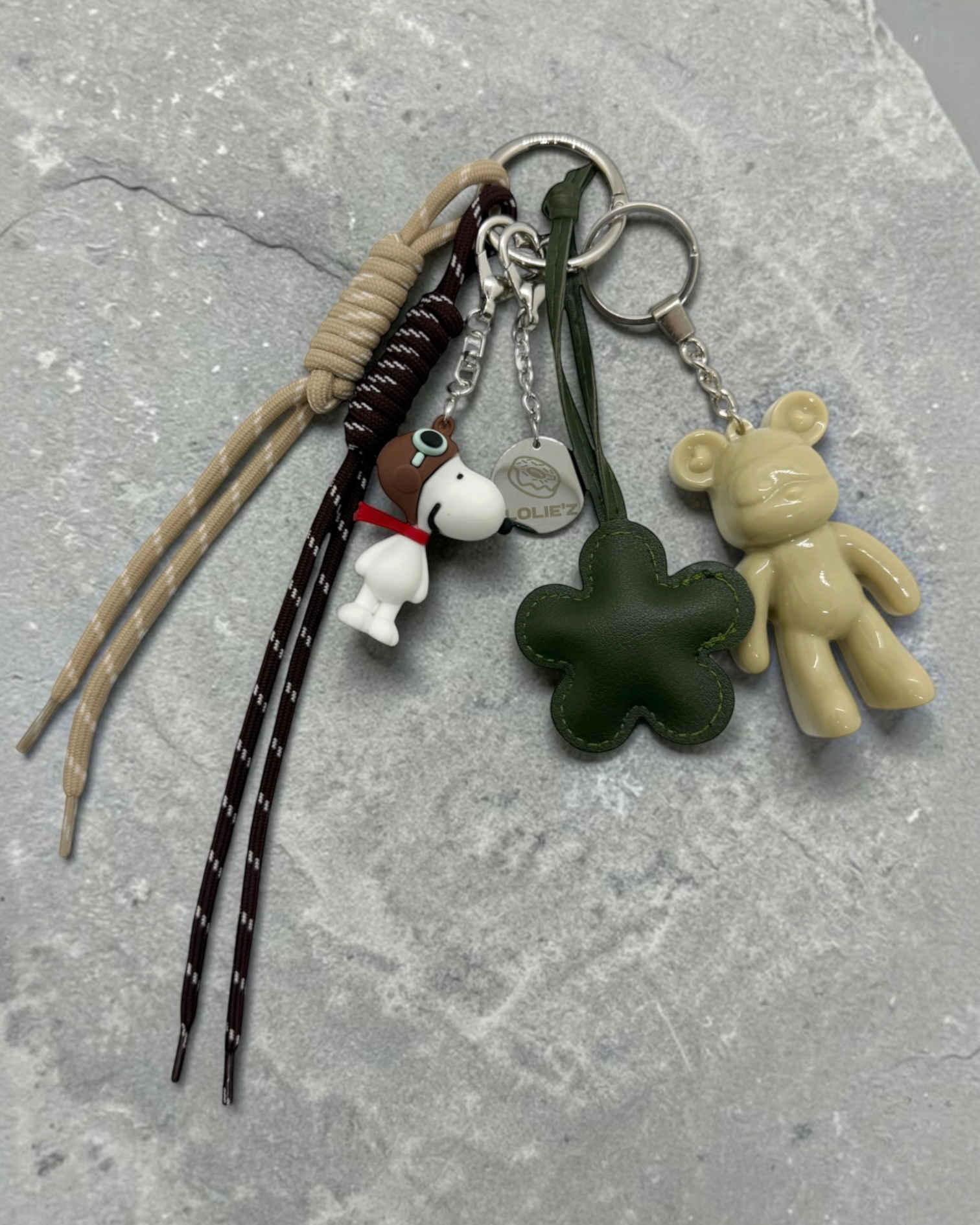 Grigri de sac Lolie’z aux tons crème, vert et marron avec Teddy’z en résine époxy, fleur verte, breloque chien et cordons, assemblé à la main en France.