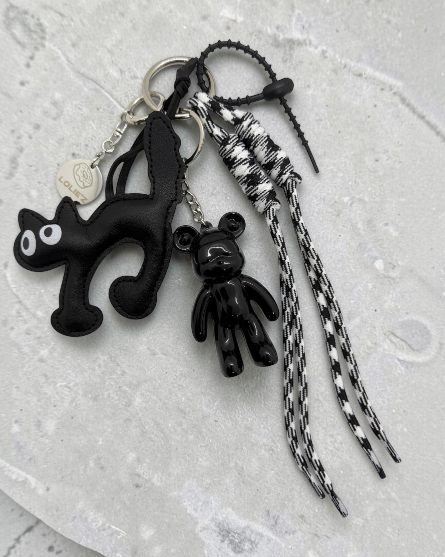 Grigri de sac Lolie’z noir et blanc avec Teddy’z en résine époxy, breloque chat noir, cordons imprimés et médaille gravée, assemblé à la main en France.