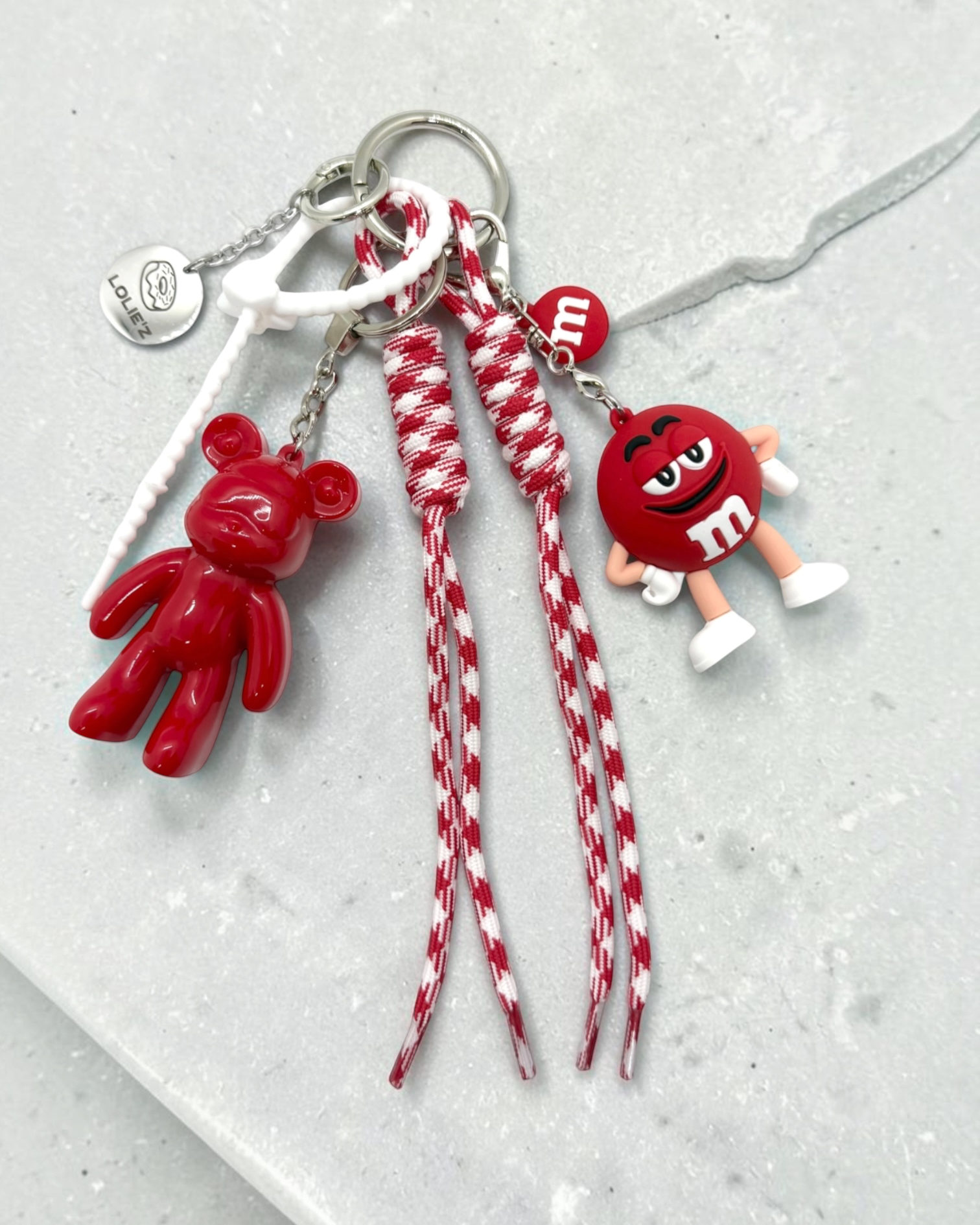 Grigri de sac rouge Lolie’z avec Teddy’z en résine époxy, cordons rouge et blanc, breloques et médaille gravée, création assemblée à la main en France.