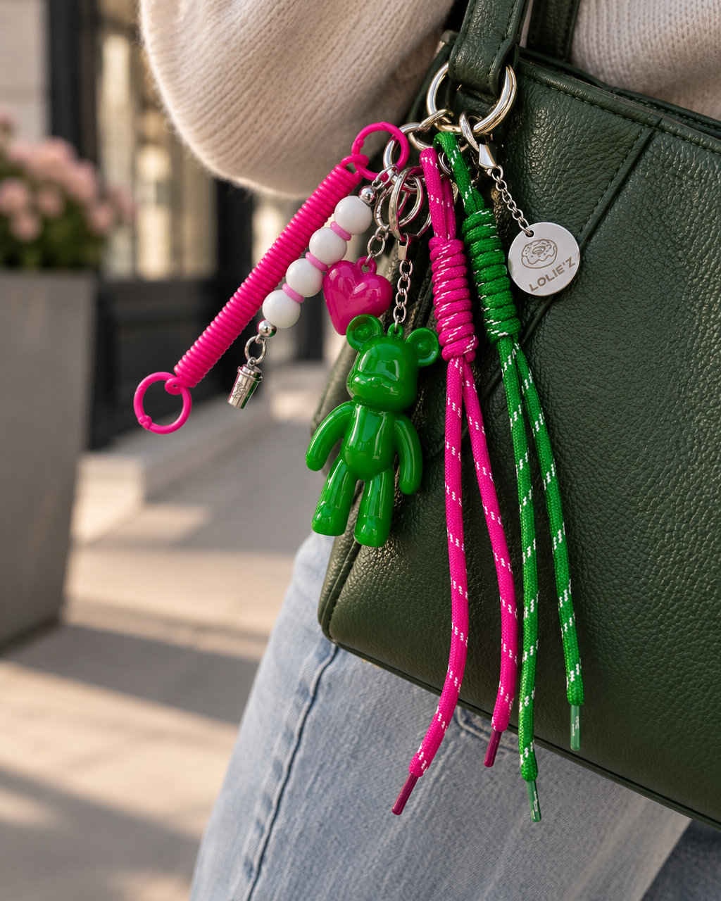 Grigri de sac Lolie’z vert et rose avec Teddy’z en résine époxy, cœur rose, cordons colorés, perles et médaille gravée, assemblé à la main en France.