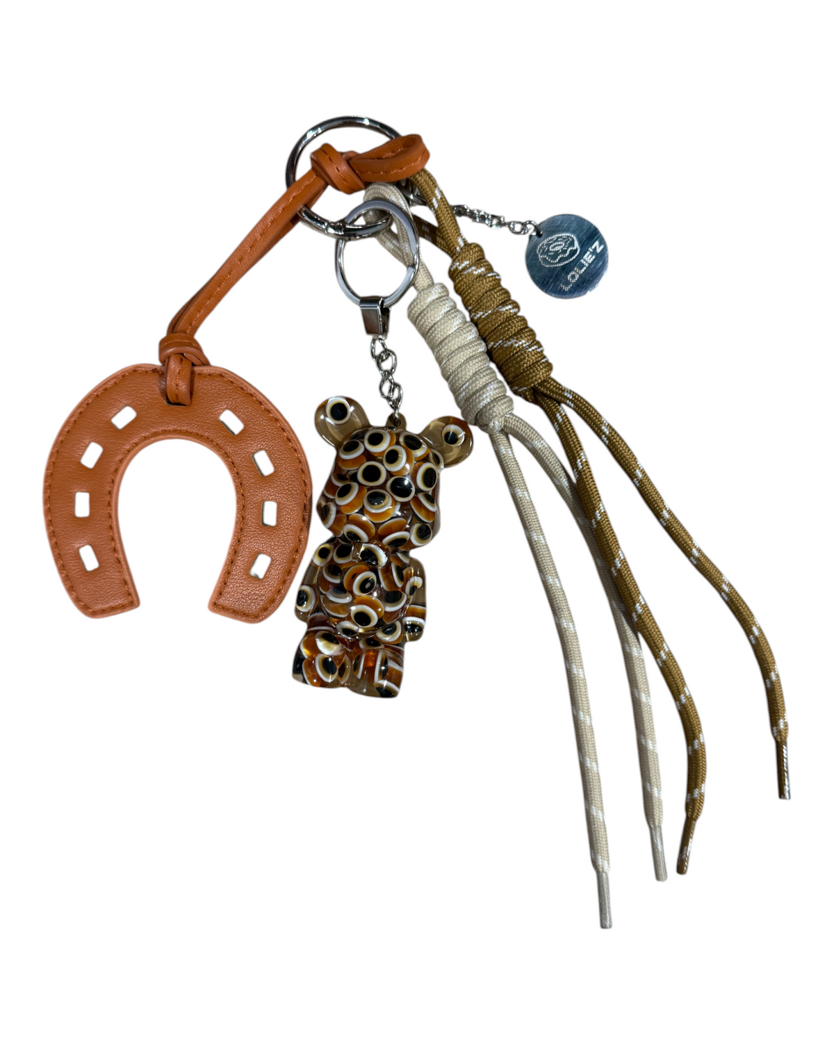 Lucky Eyes, grigri de sac fait main avec Teddy’z à motifs œil, fer à cheval camel, cordons naturels et médaille gravée Lolie’z.