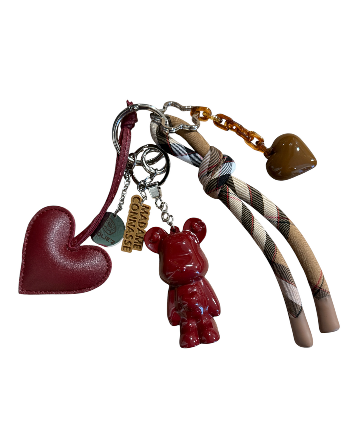 Pépitas, grigri Marley bordeaux fait main avec cœur bordeaux, ruban tartan et breloques, présenté sur fond blanc.