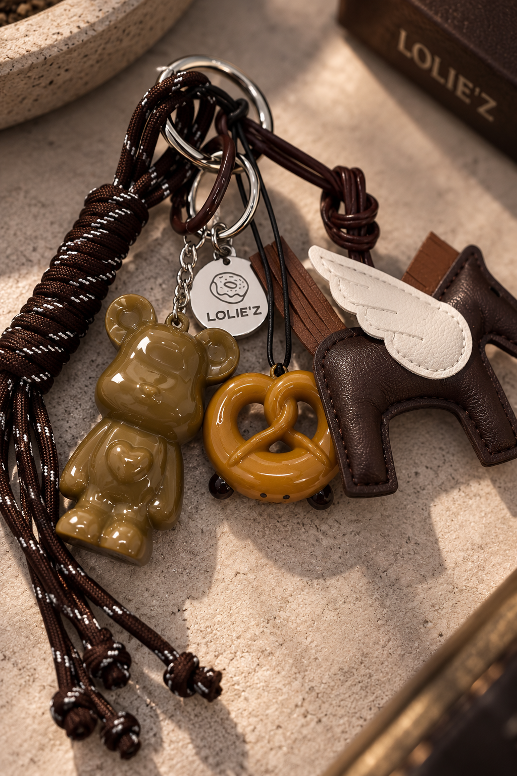 Marley Wild Ride, grigri de sac caramel en résine époxy avec cheval ailé, cordons bruns et médaille Lolie’z gravée.
