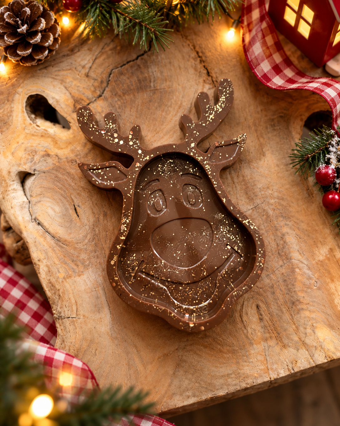Vide-poche Rudolph en résine époxy chocolat brillante avec éclats dorés, en forme de tête de renne, présenté sur une surface en bois dans une ambiance chaleureuse de Noël.